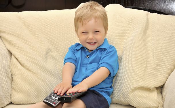 Cute kid watching tv, sitting in a very comfortable and soft cha - 写真・画像