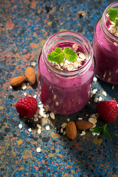 berry smoothie in a bottle and dark background, closeup top view - Фото, изображение