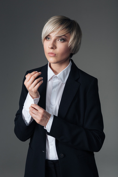 Thoughtful fashion woman buttoning her shirt - 写真・画像