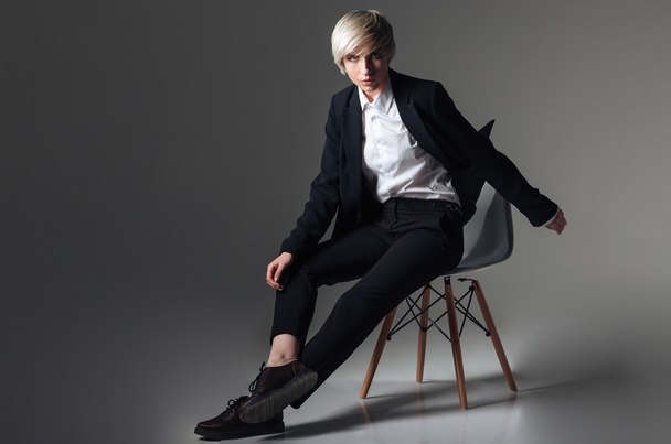 Blonde woman in fashion cloth sitting on the chair - Fotoğraf, Görsel