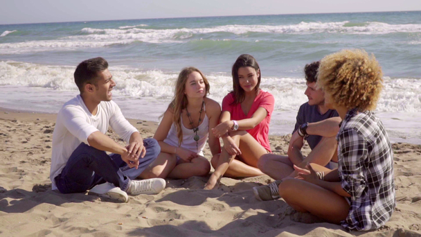 amigos sentados na areia e conversando uns com os outros
 - Filmagem, Vídeo