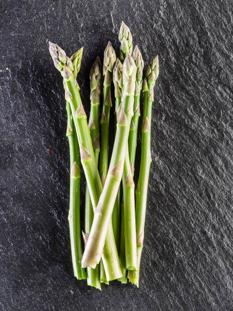 Asparagus sprouts on the black background.  - Foto, Imagen