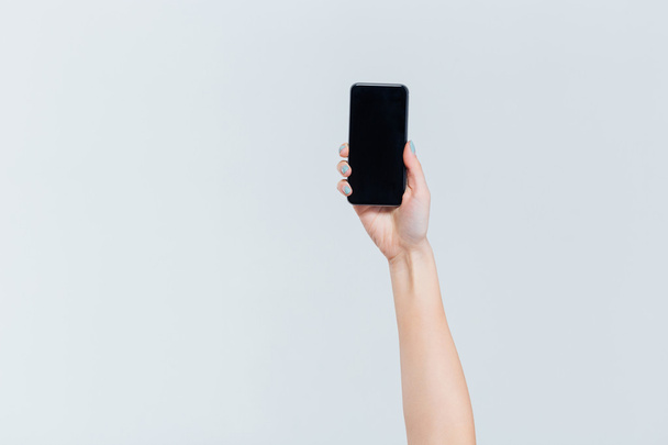 Female hand holding smartphone with blank screen - Valokuva, kuva