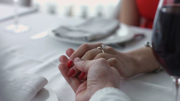Jong koppel elkaar hand in hand in het restaurant. - Foto, afbeelding