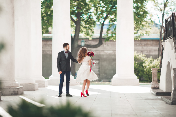 Beautiful couple, bride and groom posing near big white column - Foto, imagen