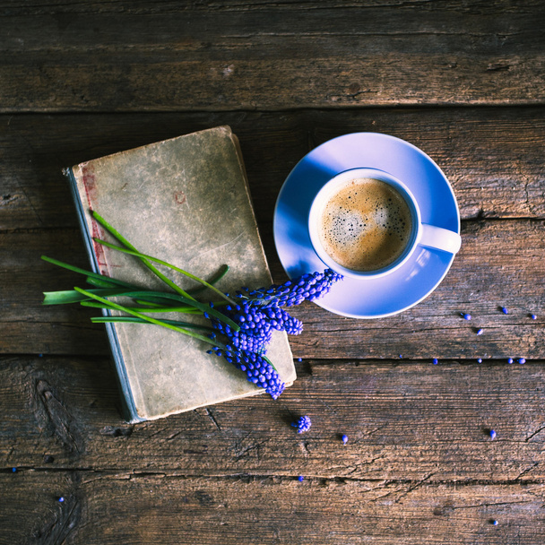 Mavi çiçekler ve bir fincan kahve ile ahşap bir arka plan üzerine bir kitap - Fotoğraf, Görsel