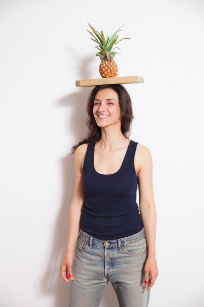 Jeune femme tenant l'ananas avec planche à découper sur la tête
 - Photo, image