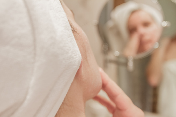 Ładna kobieta nałożeniem kremu na twarzy w łazience - Zdjęcie, obraz