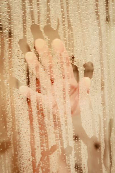 Portrait non concentré d'une femme se douchant à travers l'écran de bain
  - Photo, image