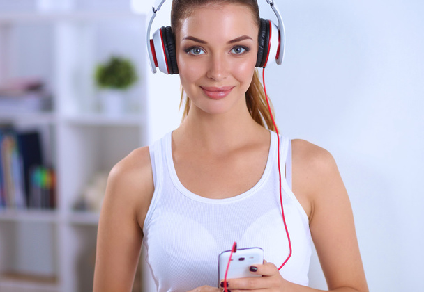 Woman with headphone listening music standing at home - Photo, Image