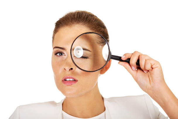 Businesswoman looking into a magnifier and have a big eye - Photo, Image