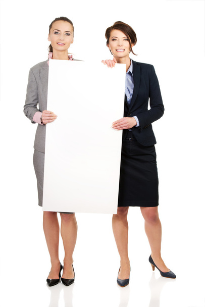 Two businesswomen carrying a big white board. - Foto, Imagem