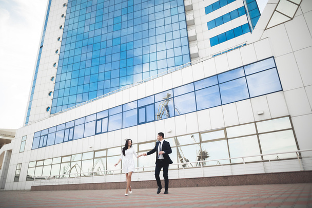 Elegant beautiful couple posing near modern glass building - Photo, image