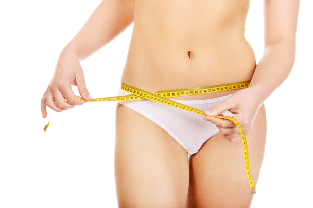 Beautiful slim woman measuring her hips - Fotografie, Obrázek