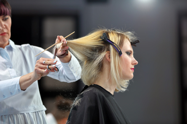 POZNAN, POLAND - MAY 07. 2016: Hairdresser trimming blond hair w - 写真・画像