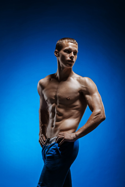 Fit young man with beautiful torso on blue background - Foto, imagen