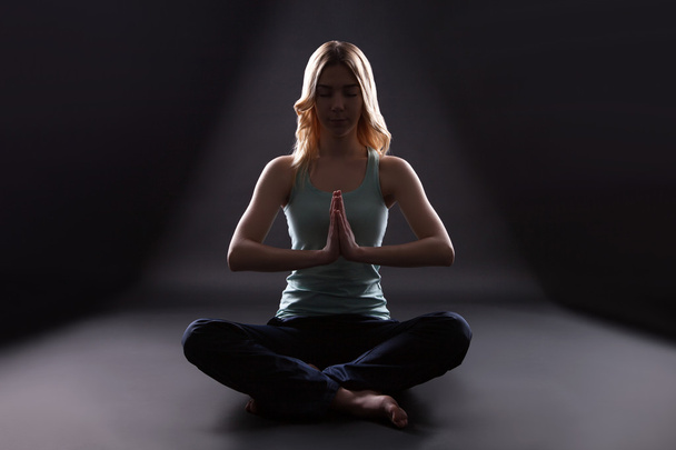 young woman sitting in lotus position isolated on black background - Foto, immagini