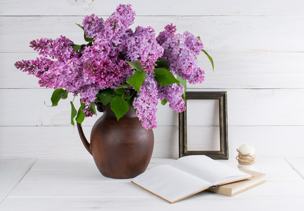 Lilac bouquet in clay jug with open book and candle in rustic st - Photo, Image