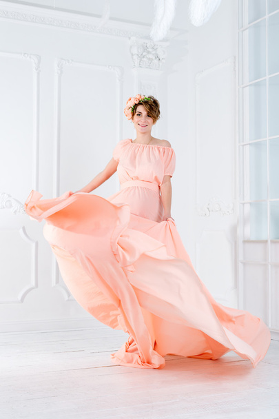 Femme enceinte dansant en robe de soirée rose volant sur le vent. Tissu ondulé, prise de vue mode
. - Photo, image