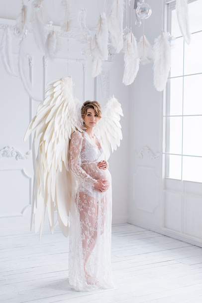 Beautiful young pregnant girl with big angel wings - Photo, Image