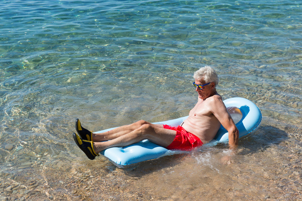 Uomo in pensione che gioca in acqua di mare
 - Foto, immagini