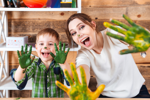 Little boy and mother showing hands painted in colorful paints  - Fotó, kép