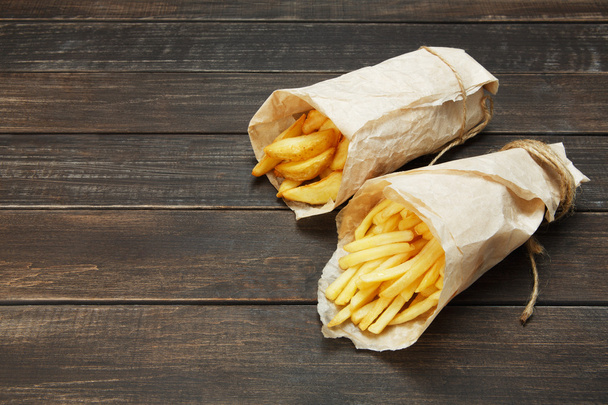 Papas fritas y cuñas de patata envueltas para llevar en madera
 - Foto, Imagen