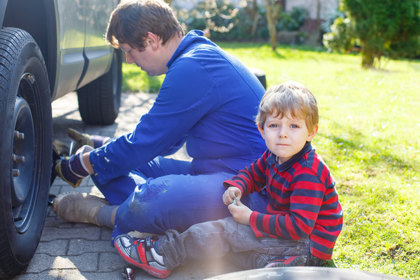 Little kid boy and his father changing wheel on car - Foto, Bild