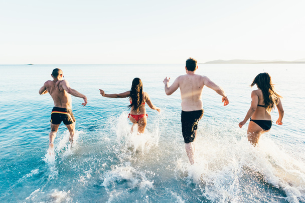 többnemzetiségű barátok fut a strandon, hogy a tenger  - Fotó, kép
