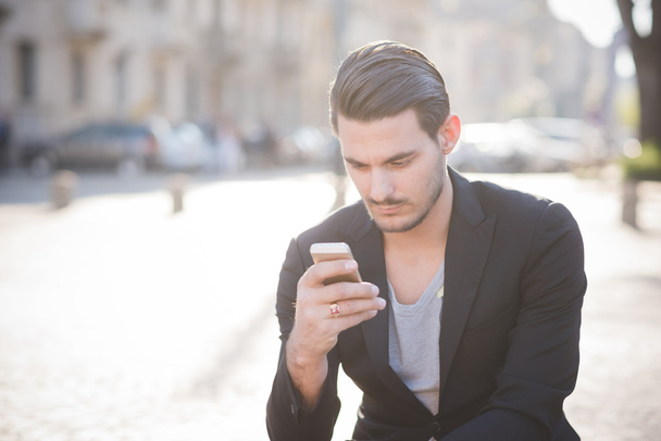 man seated on sidewalk using smartphone  - Zdjęcie, obraz