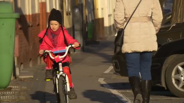 Girl is Riding the Bike Upward by City Street Opole Poland City Day Child is Riding Among the People Walking by a Vintage Street Sunny Day Spring - Filmati, video