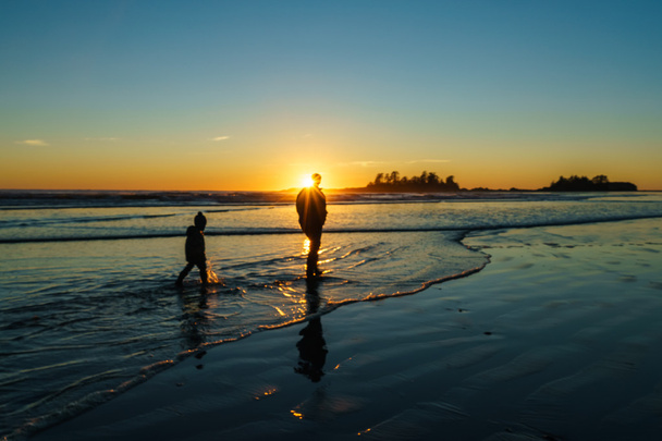 Père et fils marchant dans le surf à Chesterman Beach à Tofino
 - Photo, image