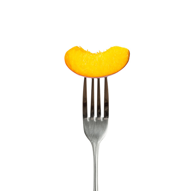 Piece of peach on fork - isolated on white background - 写真・画像