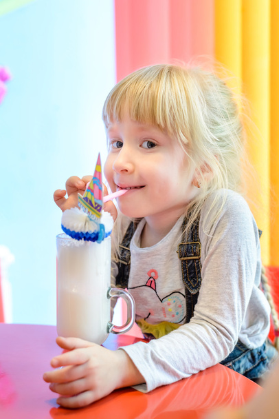 Cute pretty little girl enjoying a milkshake - Fotoğraf, Görsel