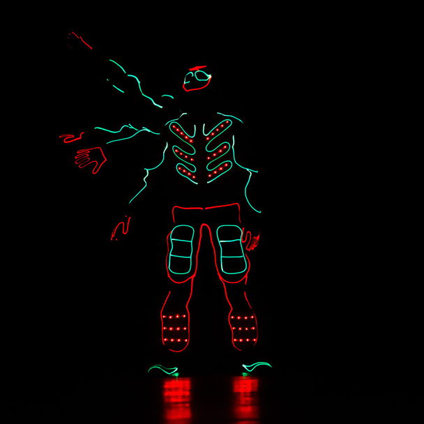 Tanssijat led-puvuissa tummalla taustalla, värillinen show
 - Valokuva, kuva