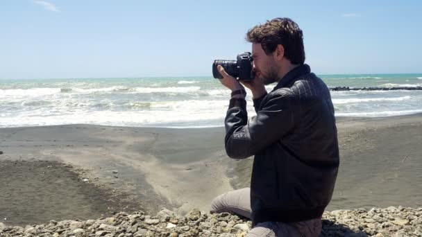 Komea mies ottaa kuvia ammatillinen kamera edessä meressä
 - Materiaali, video