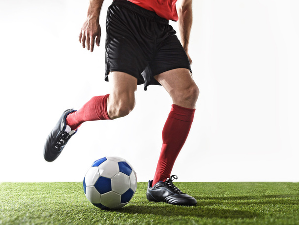 jugador de fútbol en calcetines rojos y zapatos negros corriendo y goteando con la pelota jugando en la hierba
 - Foto, imagen