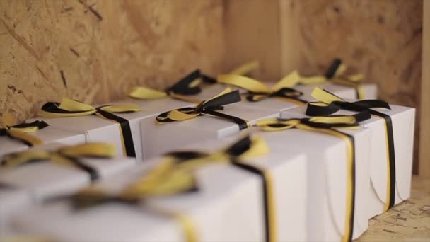 Many white box tied by black and yellow bows, tapes stay on wooden surface. Prize. Gift. Festival - Footage, Video