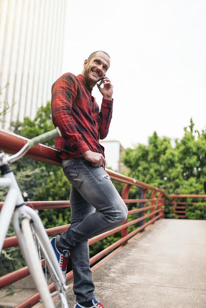 Young man with mobile phone and fixed gear bicycle. - Zdjęcie, obraz