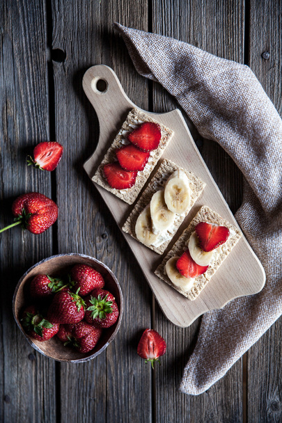 Fruity toast on wooden background. Strawberries, bread, butter and cheese.Vintage style - Foto, Imagem