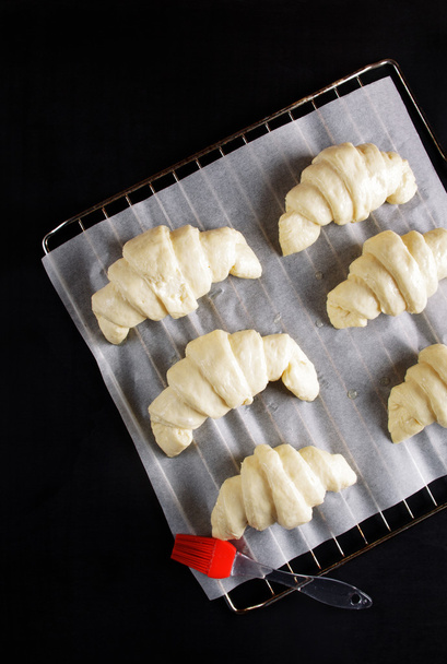 ready for baking croissants on a baking sheet for baking. brush  - Foto, afbeelding