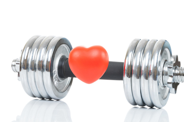 Glossy chromed dumbbell with toy heart in front of it as symbol of healthy heart - studio shot - Photo, Image