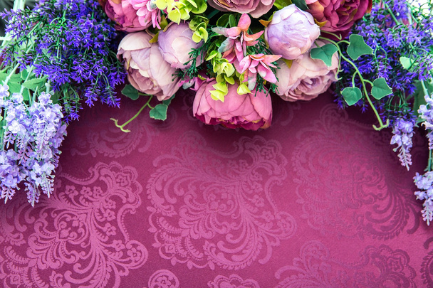Штучний квітковий букет на тлі малинового столу
 - Фото, зображення