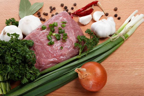 rauw vlees, groenten en kruiden geïsoleerd op een houten tafel. - Foto, afbeelding