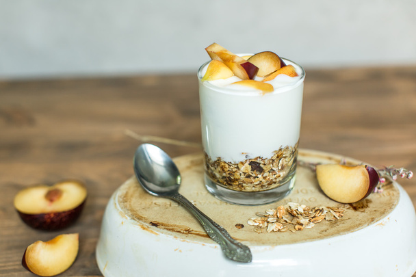 glass of granola, cereal, yogurt with peach and plum - Foto, Imagen