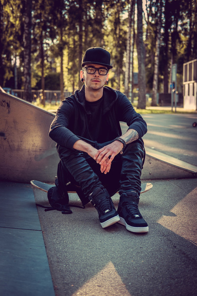 homem em roupas pretas posando com skate
 - Foto, Imagem