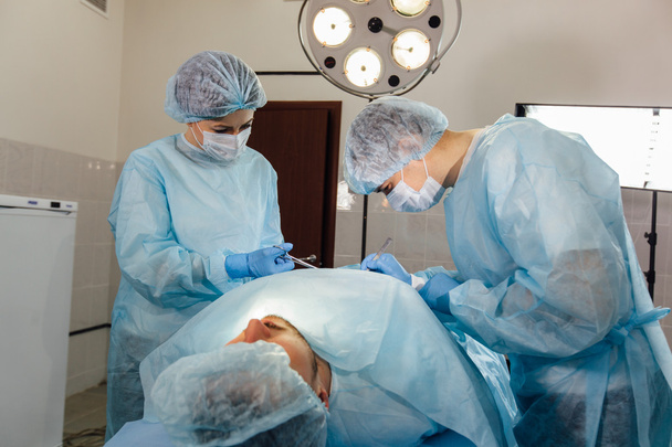 Χειρουργοί ομάδα εργασίας με παρακολούθηση του ασθενούς στη χειρουργική αίθουσα χειρουργείου. - Φωτογραφία, εικόνα