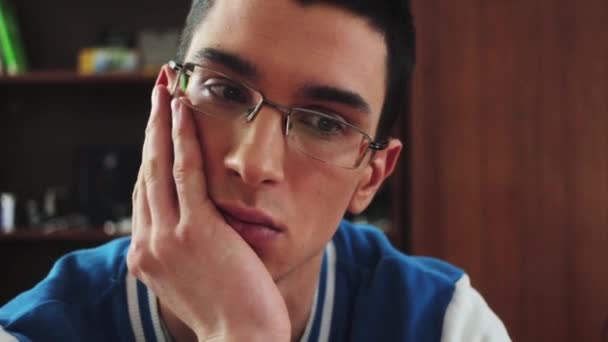 Portrait of young boy in glasses serious look in screen. Hold hand at cheek. Student. Boring. Tired - Video, Çekim