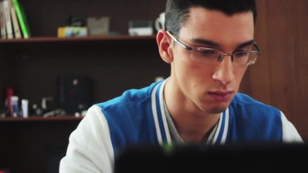 Jeune garçon dans des lunettes tapotant sur un ordinateur portable avec un visage sérieux. Touche la tête. Fatigue. Étudiant
. - Séquence, vidéo