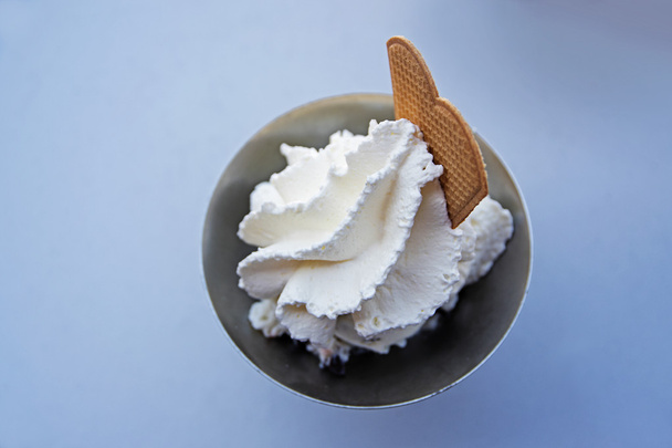 whipped cream and a biscuit over barely visible ice cream in a metalic bowl - Fotoğraf, Görsel